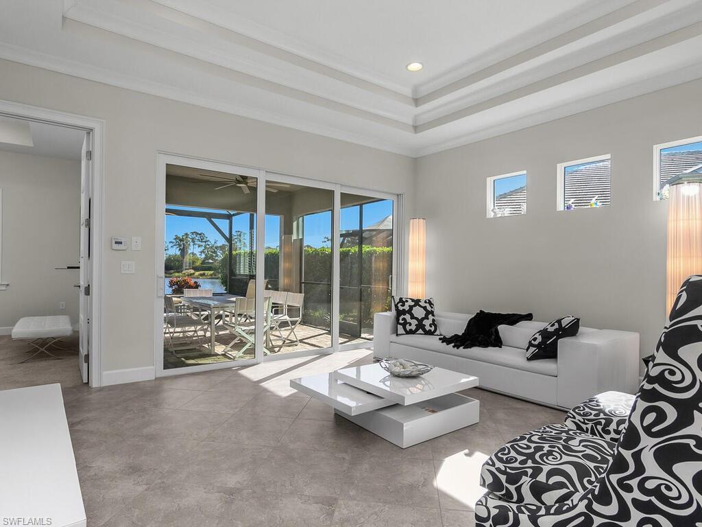 Image 2: Living room leads to the lanai and pool area, a raised ceiling, recessed lighting, and ornamental molding.