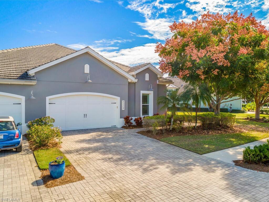 Image 3: Coastal-style home with a tiled roof, brick paver driveway, stucco siding, and an attached 2 Car garage