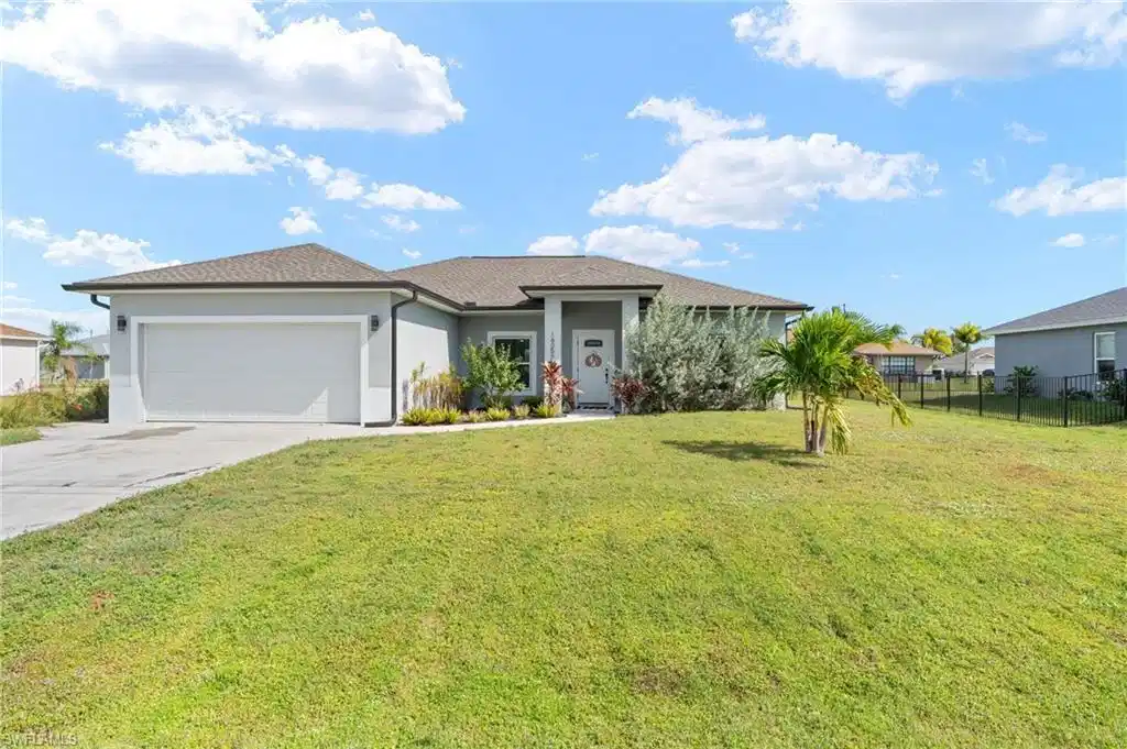 Image 1: View of front facade with stucco siding, driveway, and an attached garage