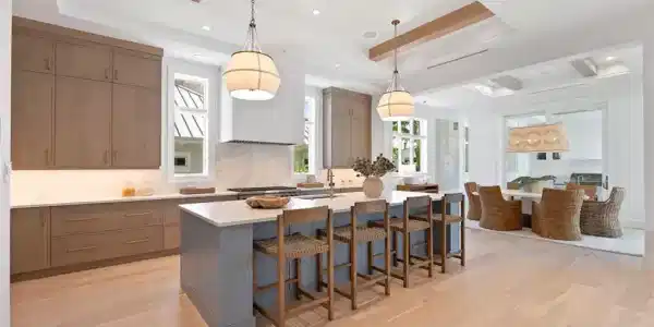 Image 4: Kitchen featuring hanging light fixtures, a kitchen bar, an island with sink, light wood-style floors, and beamed ceiling