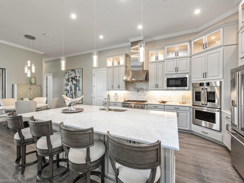 Image 2: Kitchen with decorative light fixtures, a kitchen breakfast bar, tasteful backsplash, stainless steel appliances, and crown molding