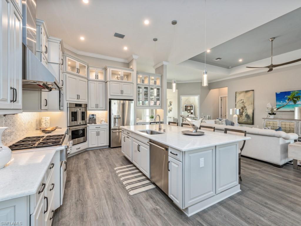 Image 3: Kitchen with hanging light fixtures, open floor plan, appliances with stainless steel finishes, white cabinetry, and recessed lighting