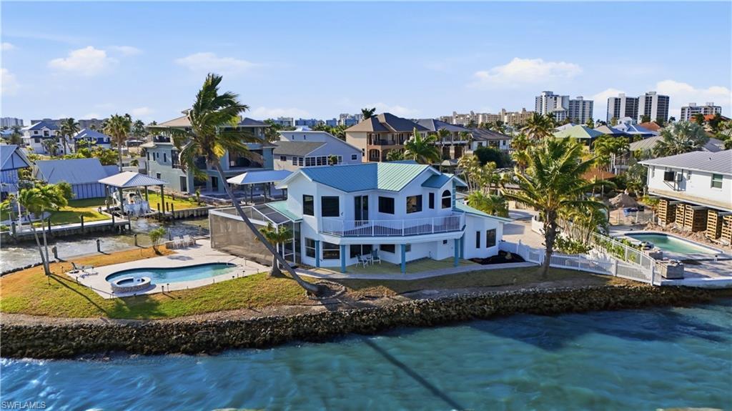 Image 2: Aerial view of residential area with a pool and a large body of water - Virtually Edited Image