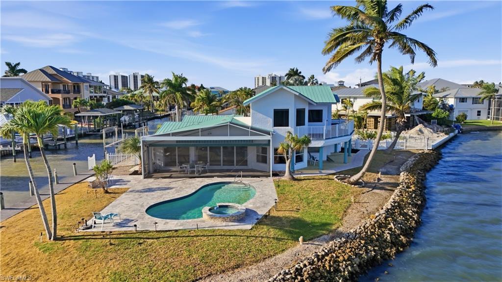 Image 4: Back of house with a sunroom, a water view, a metal roof, and a patio area - Virtually Edited Image