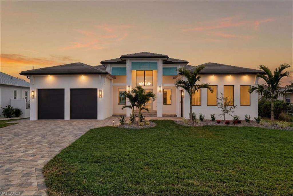 Image 1: Prairie-style house with a front lawn, decorative driveway, an attached garage, and stucco siding