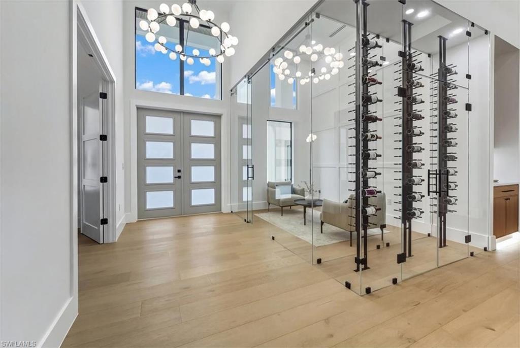 Image 4: Wine room featuring light wood-style flooring, a chandelier, french doors, and a high ceiling