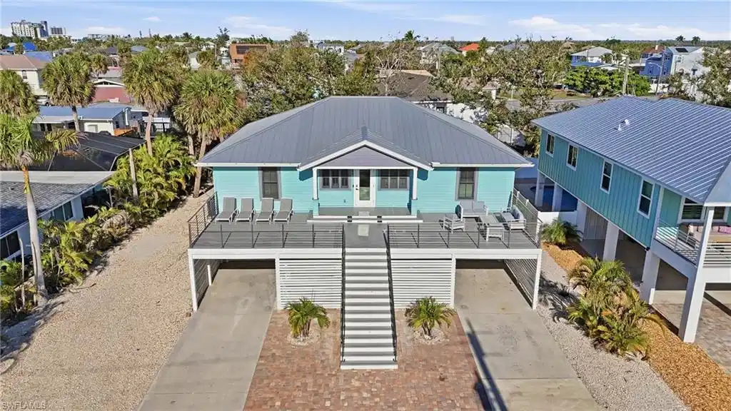 Image 1: Coastal inspired home featuring stairway, a garage, a balcony, driveway, and a metal roof - Virtually Edited Image