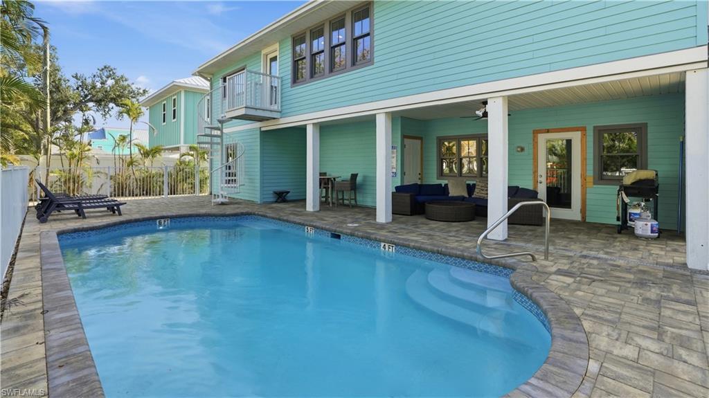 Image 3: View of pool with outdoor lounge area, a patio, a grill, and a balcony