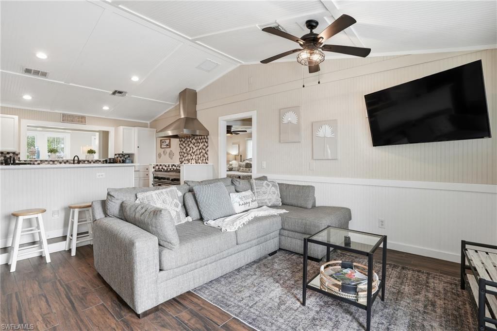 Image 4: Living room with lofted ceiling, dark wood finished floors, a wainscoted wall, and wooden walls - Virtually Edited Image