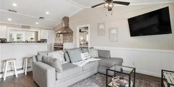 Image 4: Living room with lofted ceiling, dark wood finished floors, a wainscoted wall, and wooden walls - Virtually Edited Image