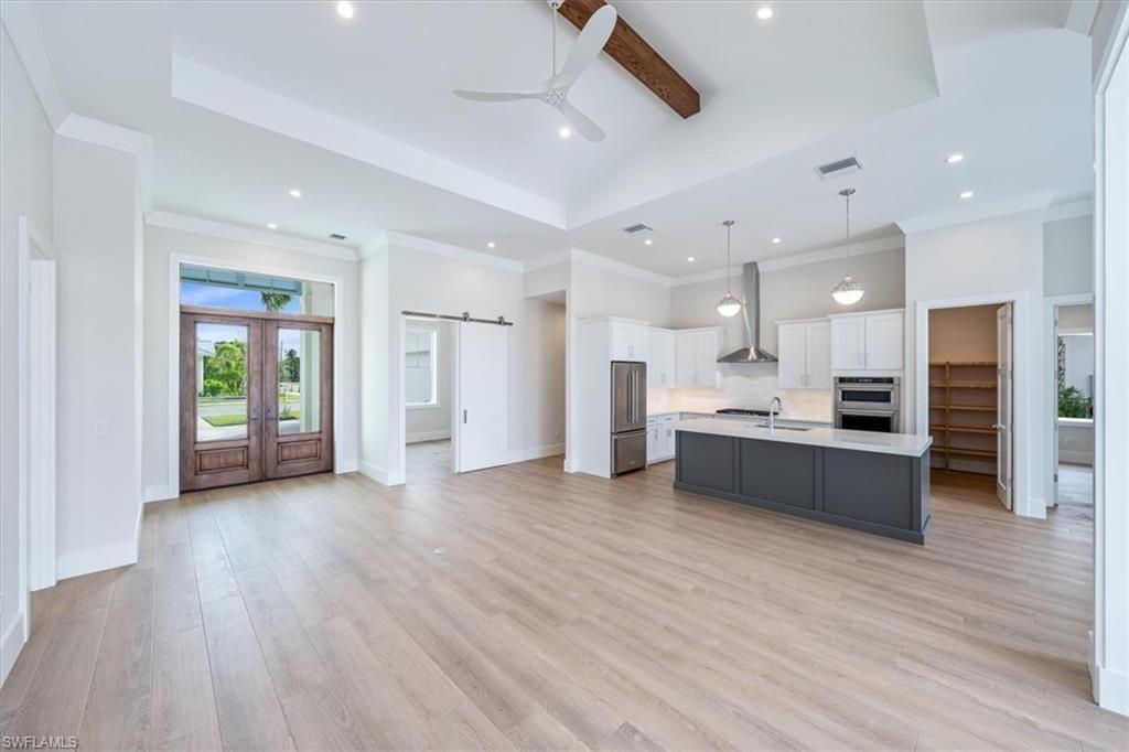 Image 3: The open concept foyer, kitchen, dining, andgreat room areas all tie in seamlessly withwarm wood accents paired with a crisp whiteand deep charcoal kitchen.