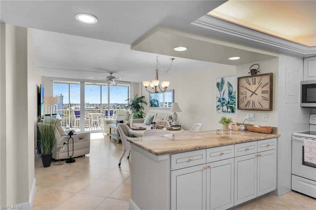 Image 2: Kitchen with a peninsula, white electric range, light stone countertops, ceiling fan, and open floor plan