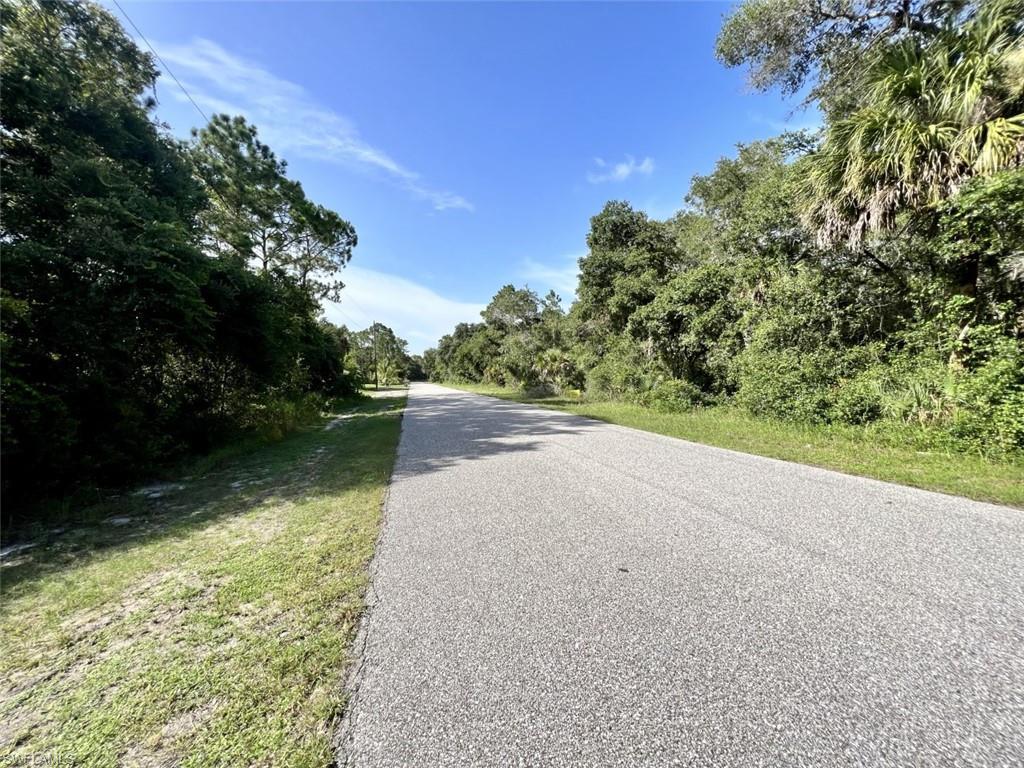 Image 3: View of asphalt street featuring a view of trees