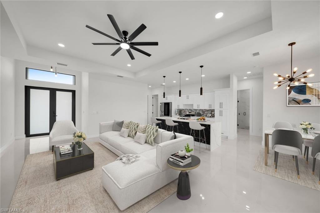 Image 3: Living area with a tray ceiling, a chandelier, recessed lighting, light tile patterned floors, and a ceiling fan