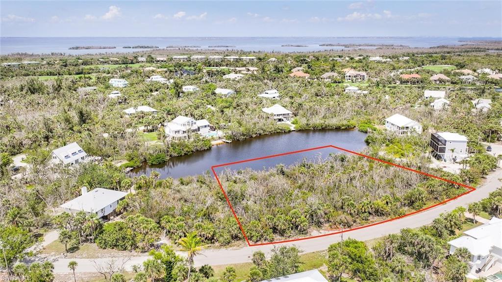 Image 1: Aerial view of residential area featuring a large body of water and property parcel outlined