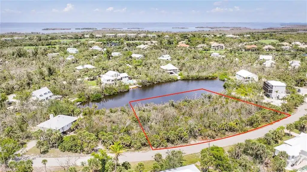 Image 1: Aerial view of residential area featuring a large body of water and property parcel outlined