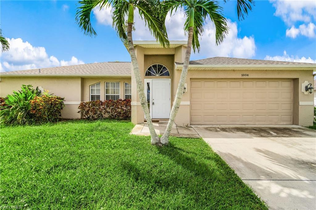 Image 1: Single story home with stucco siding, concrete driveway, a garage, and a front lawn