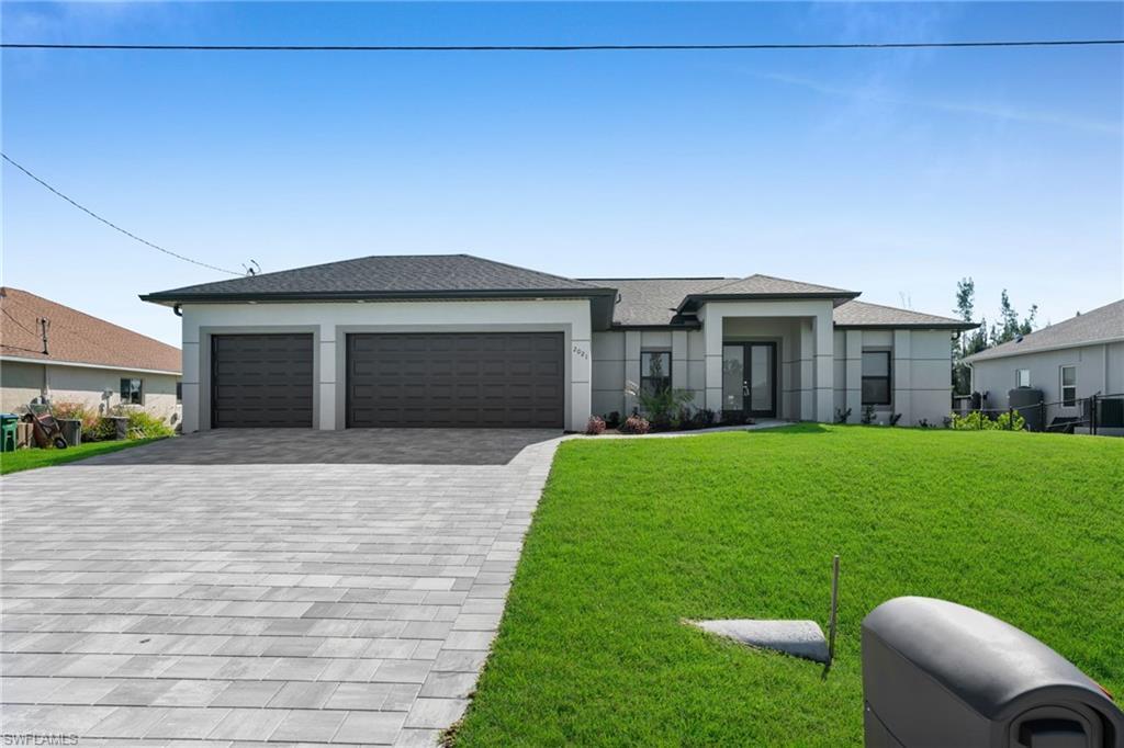 Image 1: Prairie-style home featuring a front lawn, decorative driveway, stucco siding, and a garage