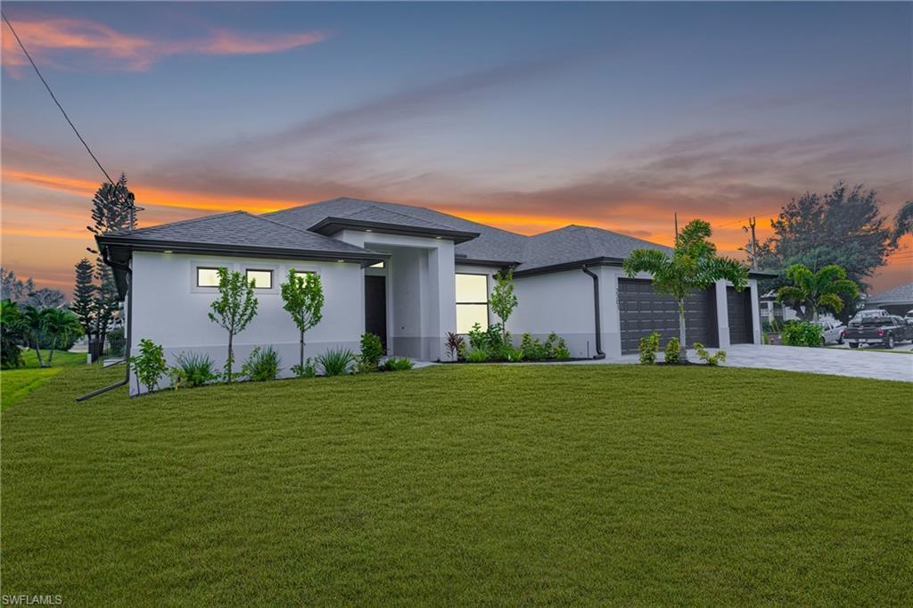Image 2: Prairie-style home featuring a yard, stucco siding, driveway, and a garage