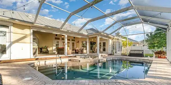 Image 4: View of pool with an outdoor hangout area, a patio area, glass enclosure, a sunroom, and french doors