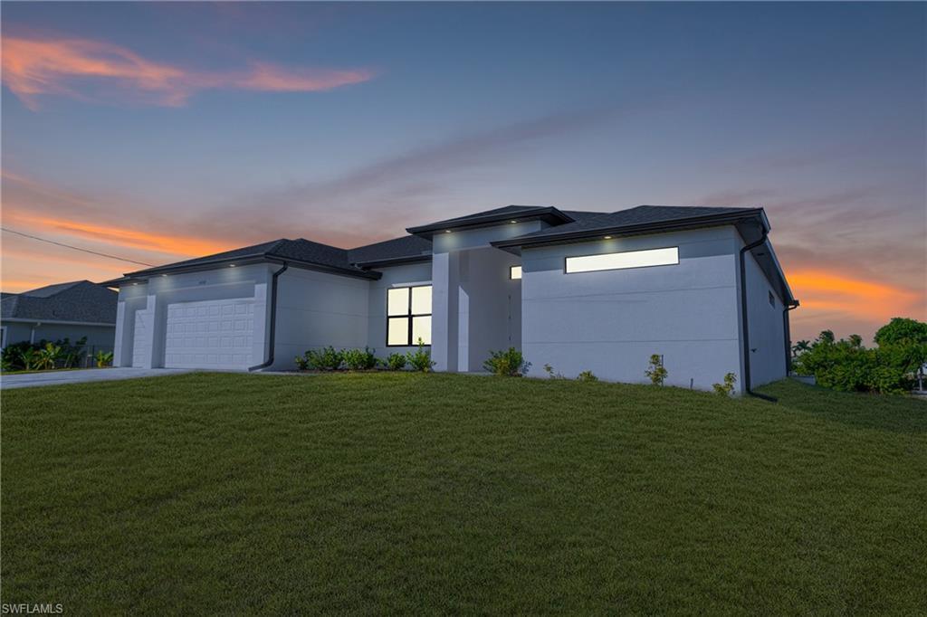 Image 4: Prairie-style home with a yard, an attached garage, driveway, and stucco siding