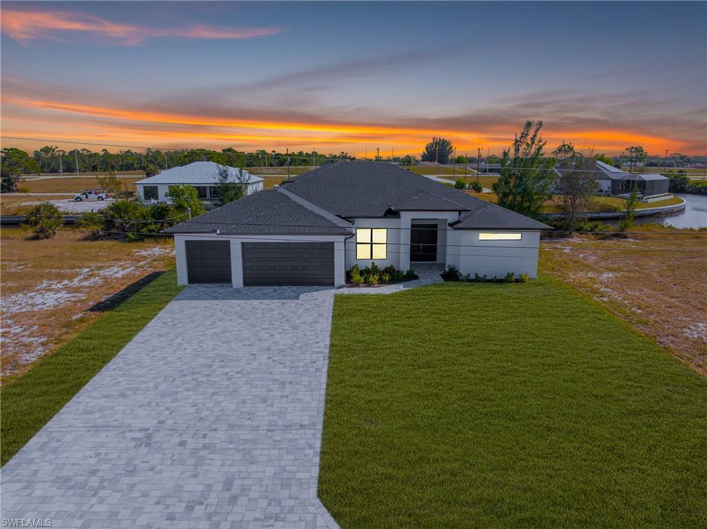 Image 1: View of front facade with decorative driveway, a front lawn, an attached garage, and roof with shingles