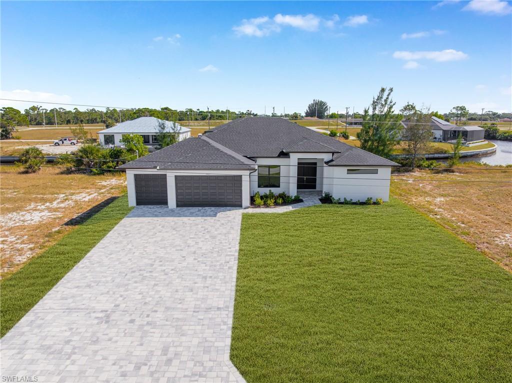 Image 2: View of front of property with a front lawn, decorative driveway, an attached garage, and a shingled roof