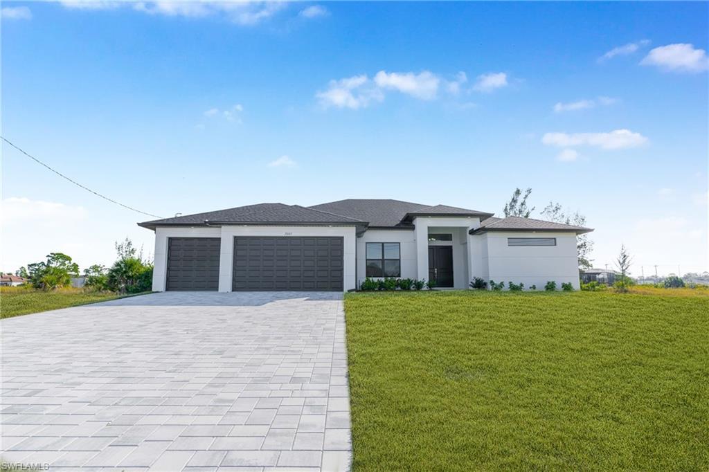 Image 3: Prairie-style house with a front lawn, decorative driveway, a garage, and stucco siding