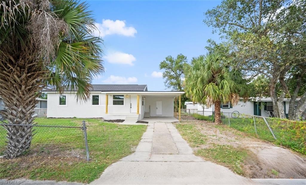 Image 1: View of front of property with stucco siding, driveway, a fenced front yard, and a porch