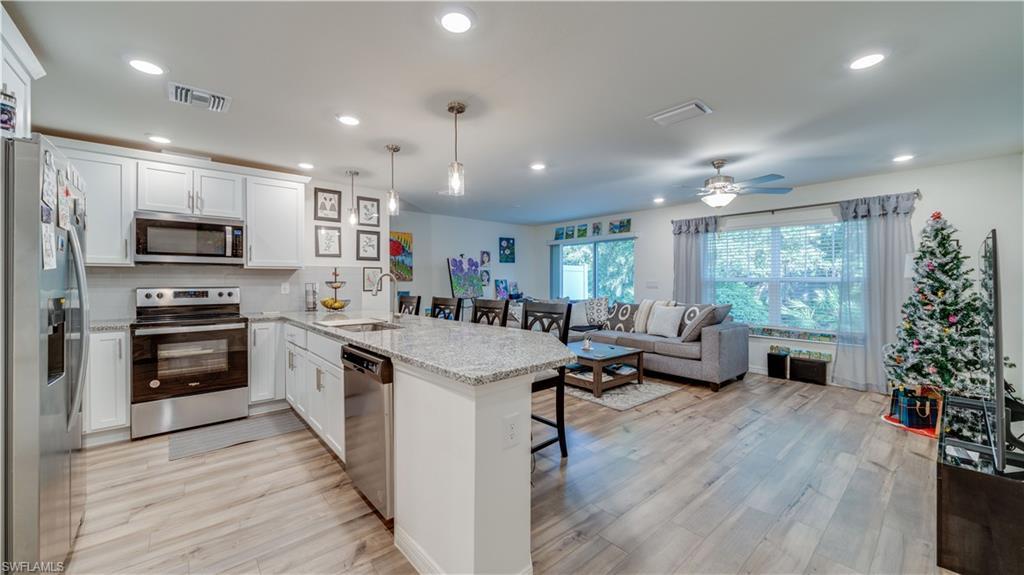 Image 4: Kitchen with stainless steel appliances, a peninsula, a kitchen breakfast bar, white cabinets, and recessed lighting