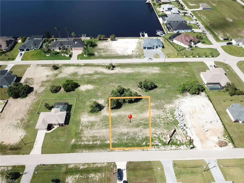 Image 2: Aerial view of residential area featuring a large body of water and property parcel outlined