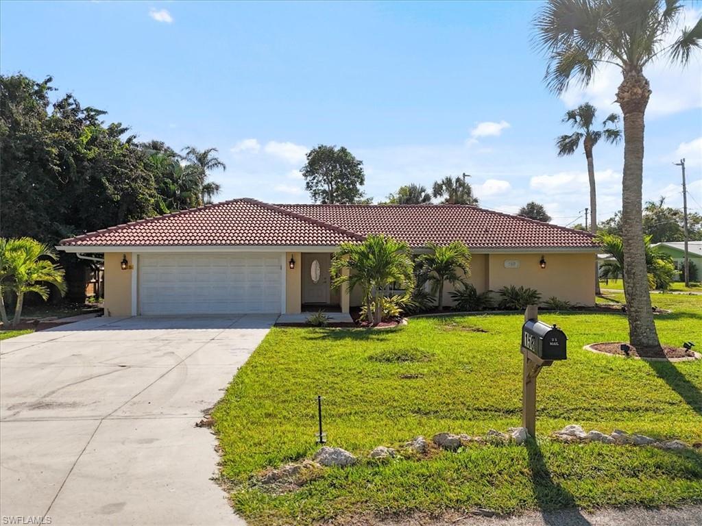 Image 2: View of front of home with a tile roof, a front yard, concrete driveway, and stucco siding