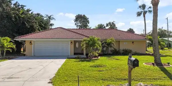 Image 2: View of front of home with a tile roof, a front yard, concrete driveway, and stucco siding