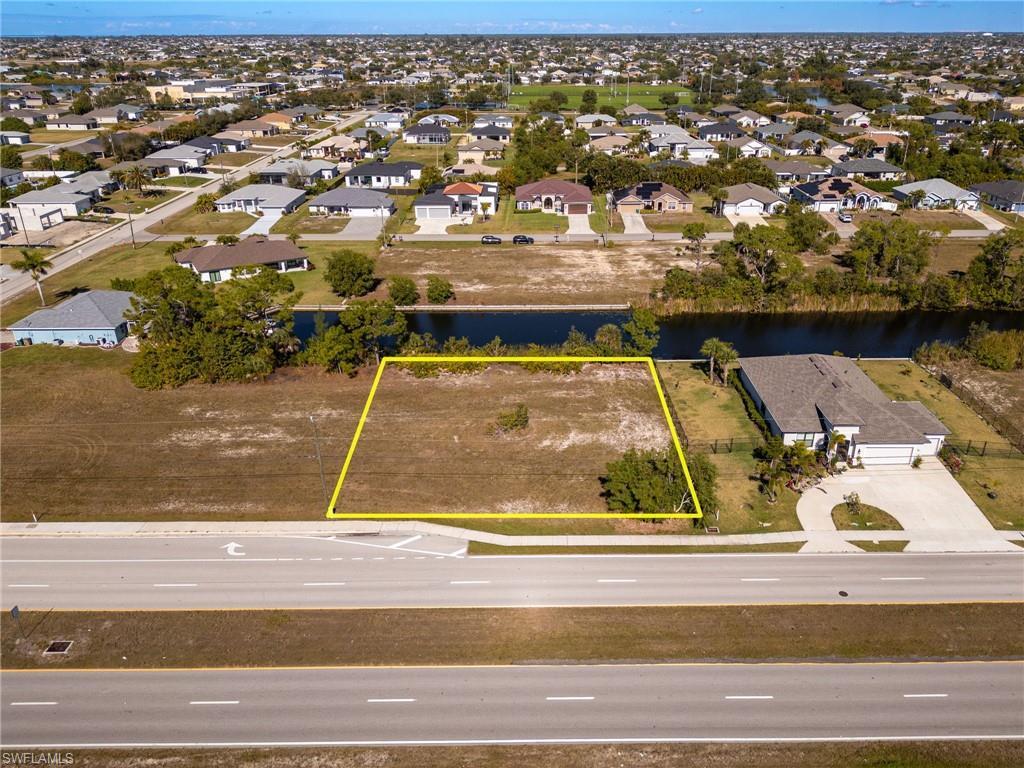 Image 3: Aerial view of residential area featuring property parcel outlined and a large body of water