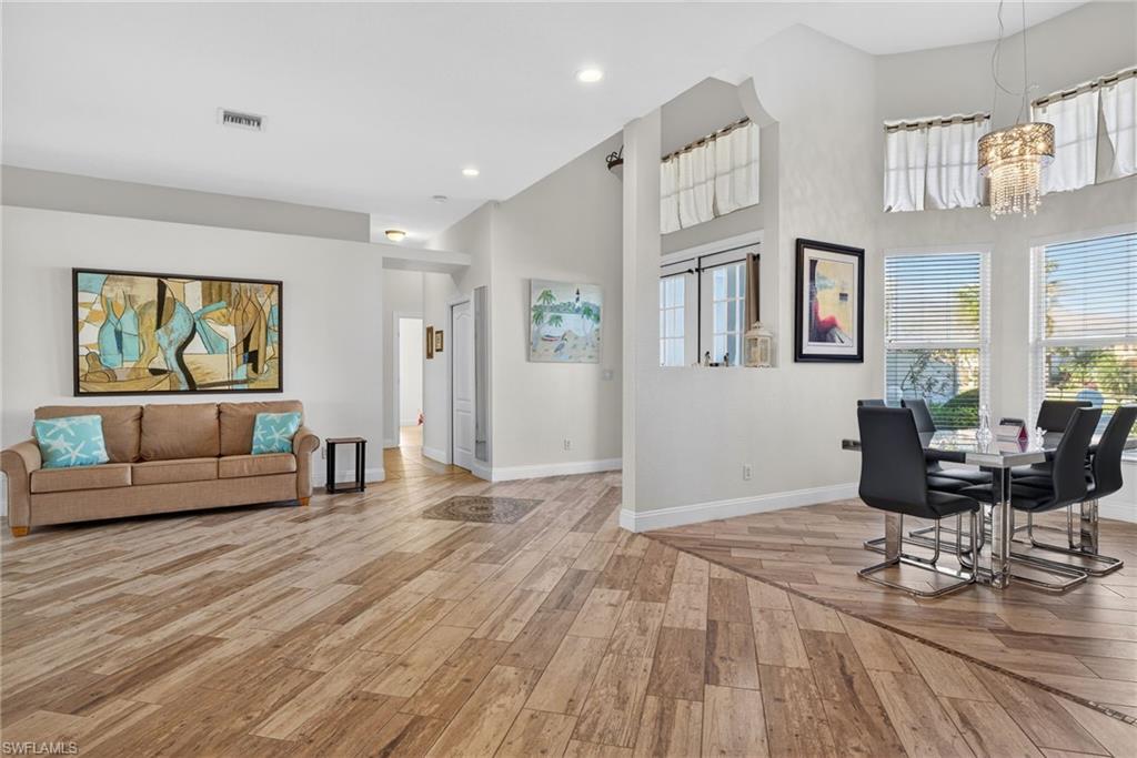Image 4: Dining room featuring a towering ceiling, light wood-style flooring, and a chandelier