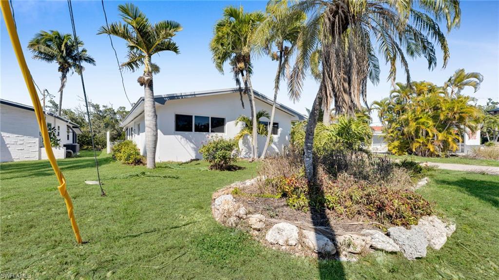 Image 3: View of property exterior with a yard and stucco siding