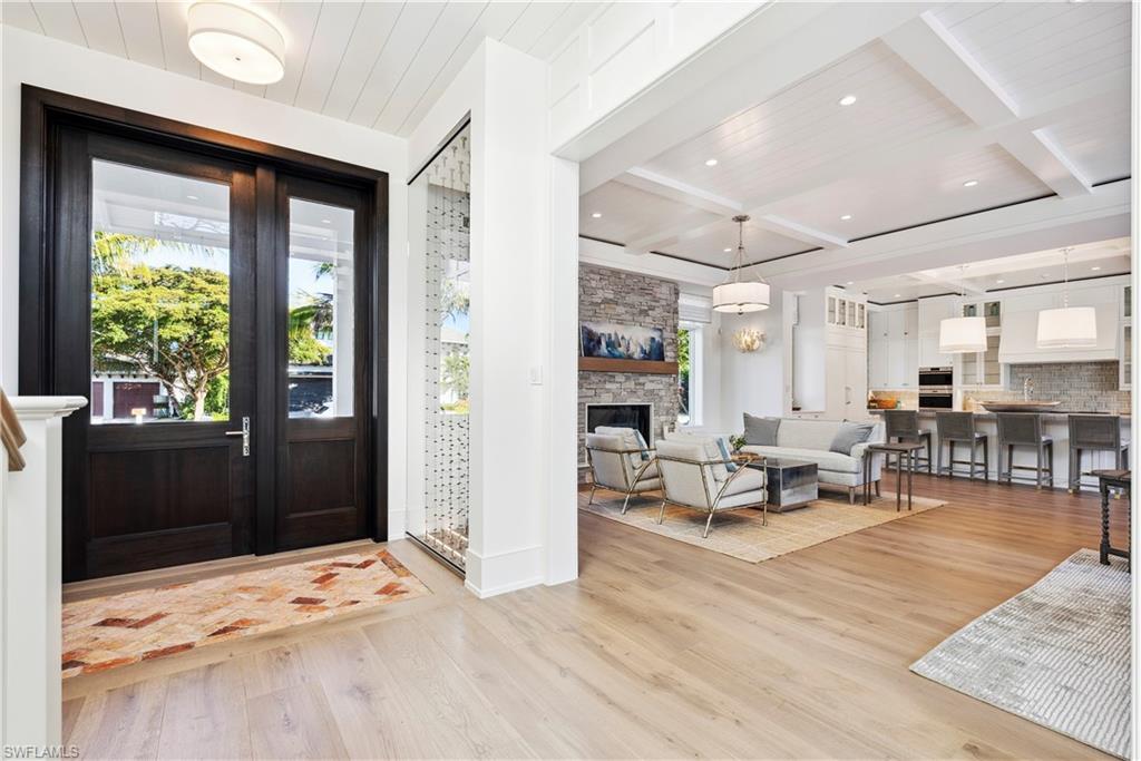 Image 4: Foyer with a stone fireplace, beamed ceiling, coffered ceiling, wooden ceiling, and light wood-type flooring