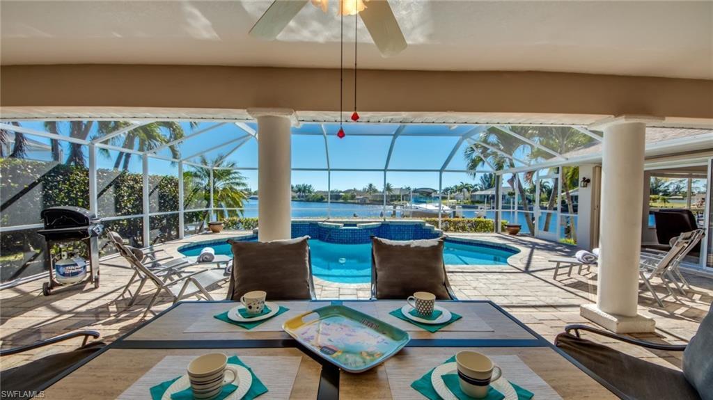 Image 2: View of swimming pool with glass enclosure, a water view, a patio, and grilling area