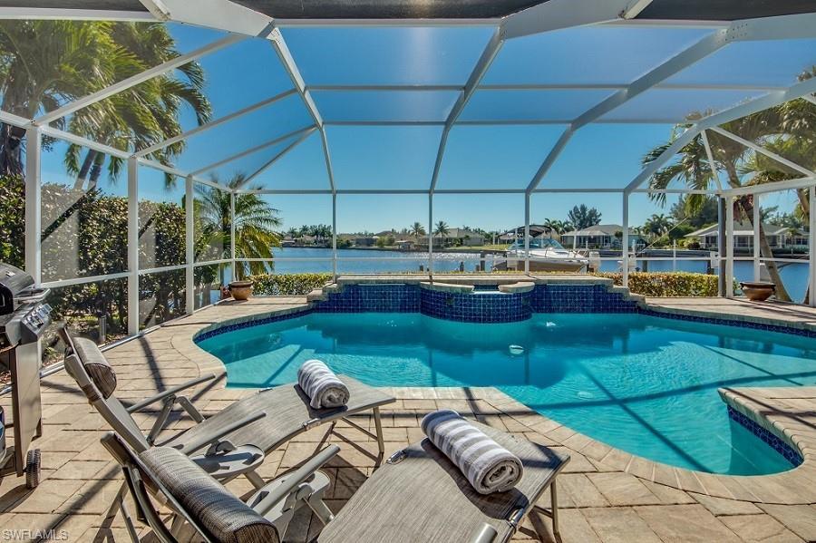 Image 3: View of swimming pool featuring a water view, glass enclosure, and a patio area