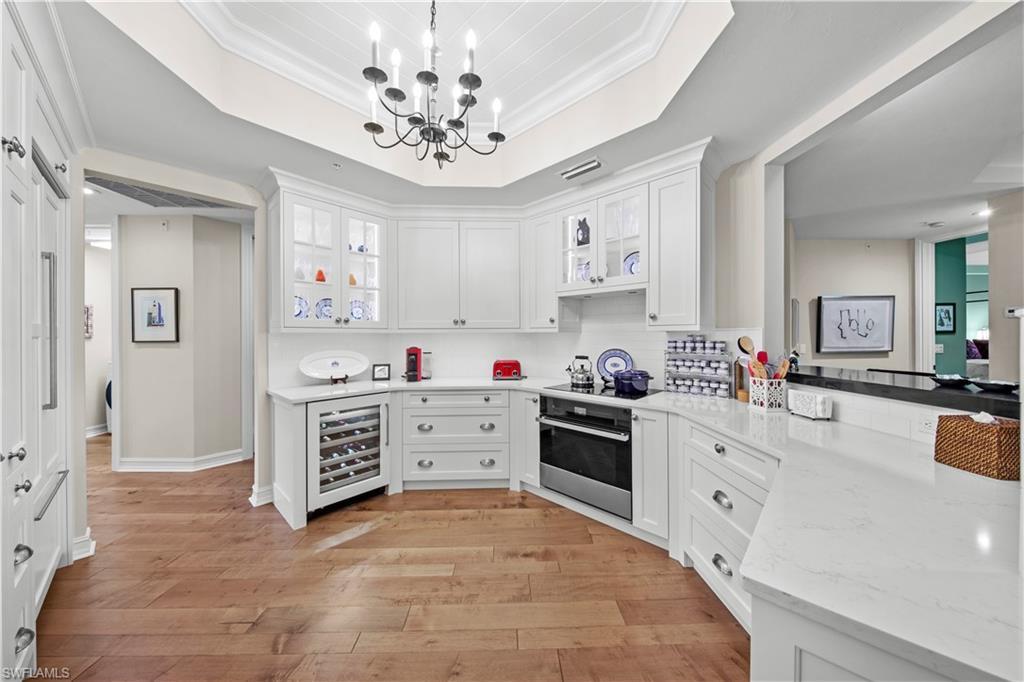 Image 3: Kitchen with pendant lighting, beverage cooler, white cabinets, oven, and crown molding