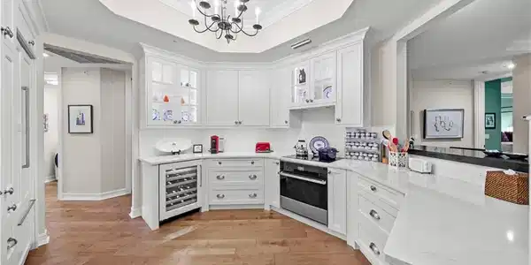 Image 3: Kitchen with pendant lighting, beverage cooler, white cabinets, oven, and crown molding