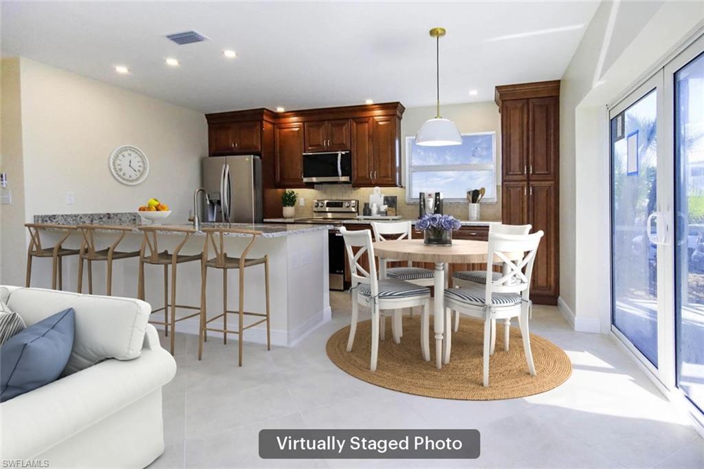 Image 2: Kitchen with a breakfast bar area, pendant lighting, stainless steel appliances, light stone countertops, and backsplash
