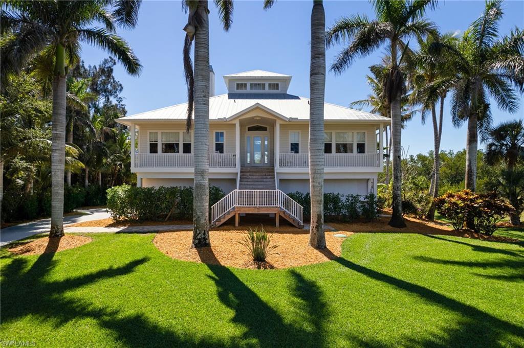 Image 1: Front of Home with open porch and Royal Palm trees