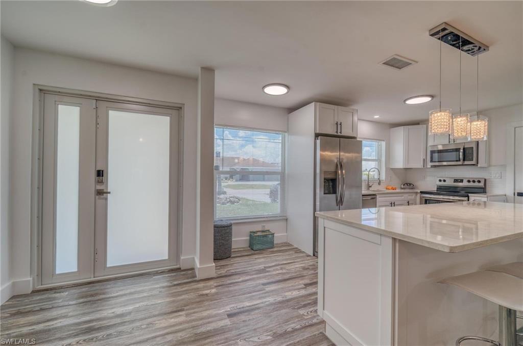 Image 3: Kitchen featuring stainless steel appliances, light stone countertops, white cabinets, light wood finished floors, and recessed lighting