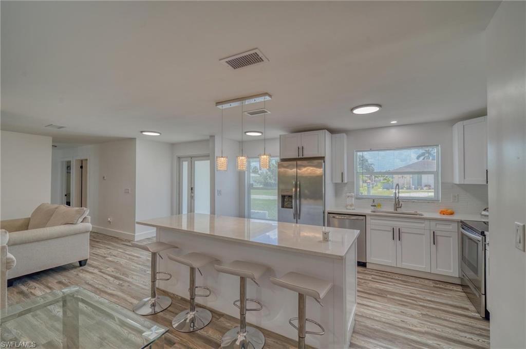 Image 4: Kitchen featuring appliances with stainless steel finishes, a sink, light countertops, white cabinets, and recessed lighting
