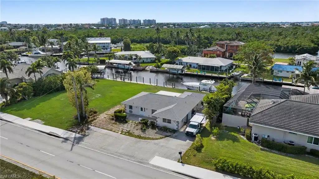 Image 1: Aerial view of residential area featuring a nearby body of water