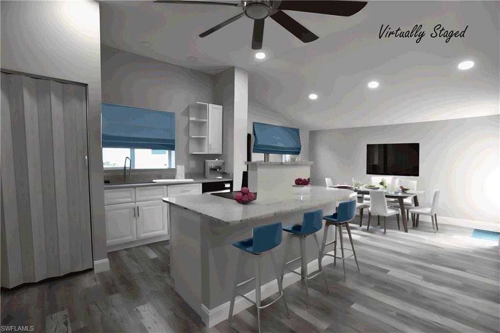 Image 3: Kitchen featuring ceiling fan, white cabinets, a center island, a breakfast bar area, and LVP floors