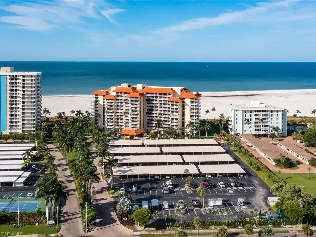Image 1: Bird's eye view of apartment complex and waterfront with a beach
