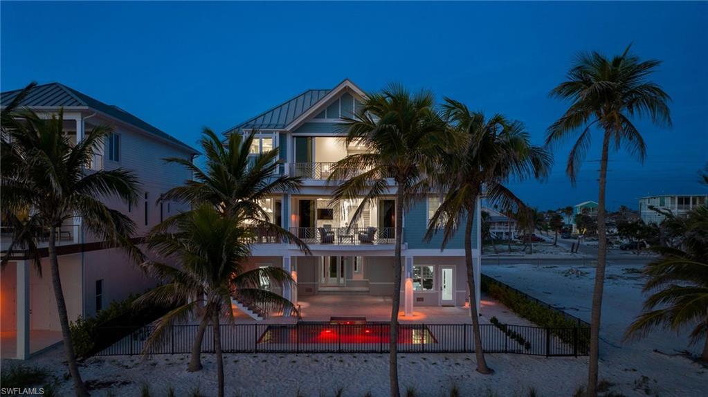 Image 3: Breathtaking Gulf-Front Estate at Sunset - the warm glow of the home contrasts beautifully with the serene Gulf waters and dramatic sunset skies- Photo Virtually Edited