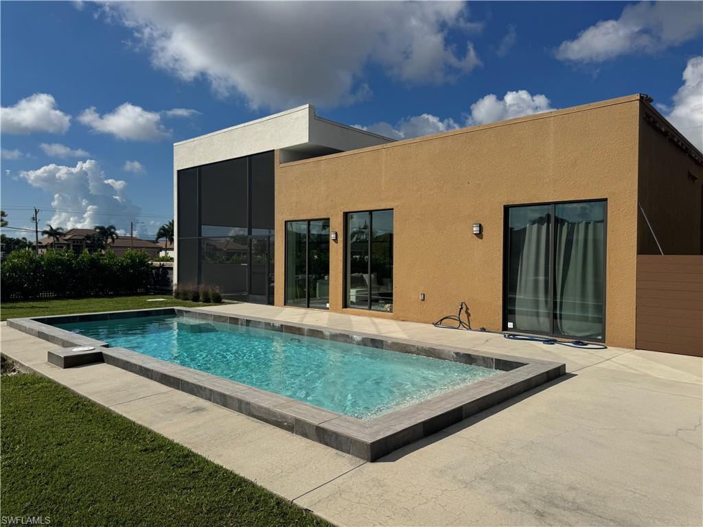 Image 1: Outdoor pool with a patio area and a lawn